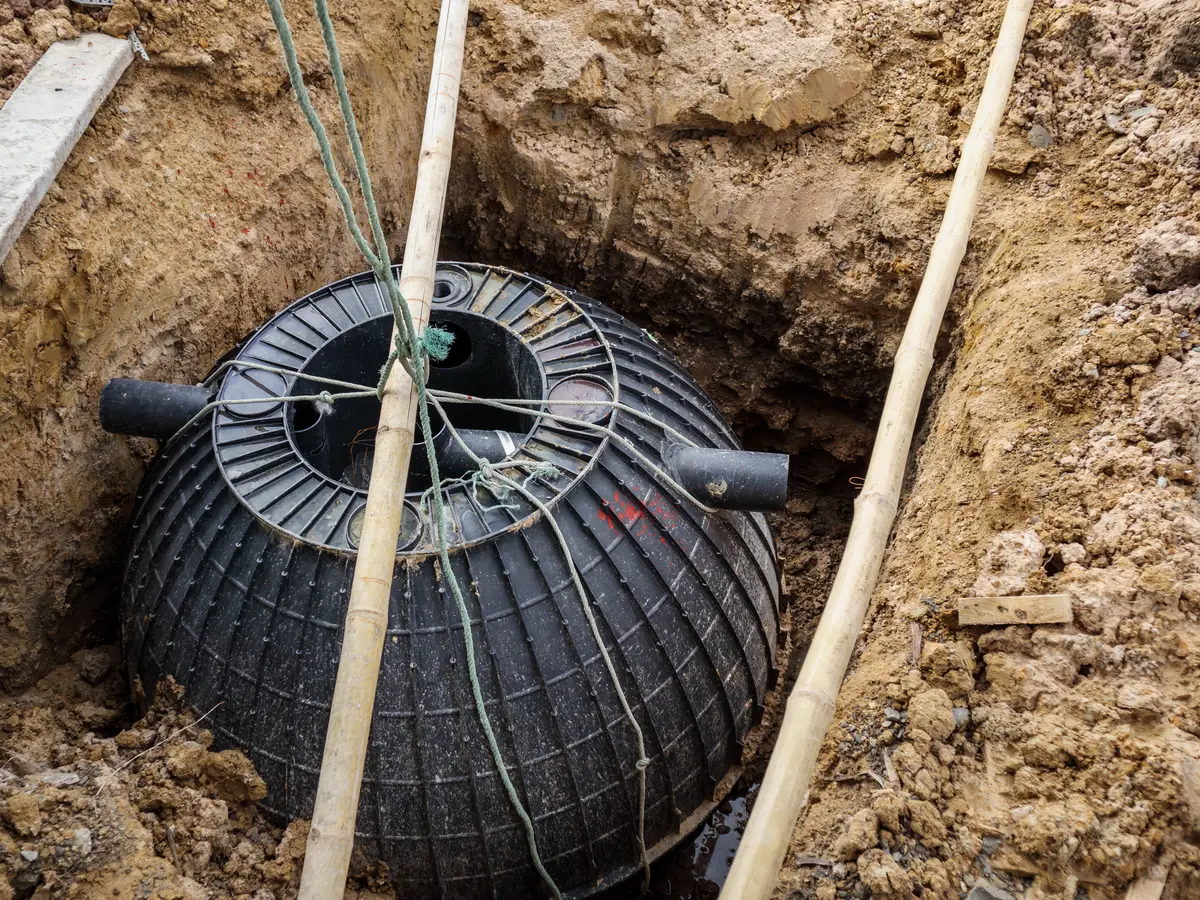Underground drainage chamber set into an excavation with pipe connections