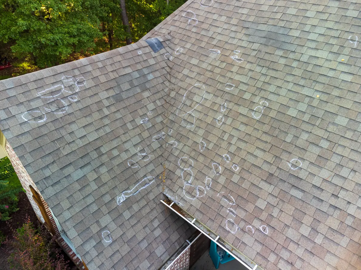 Shingle roof marked in chalk where damaged shingles have been found