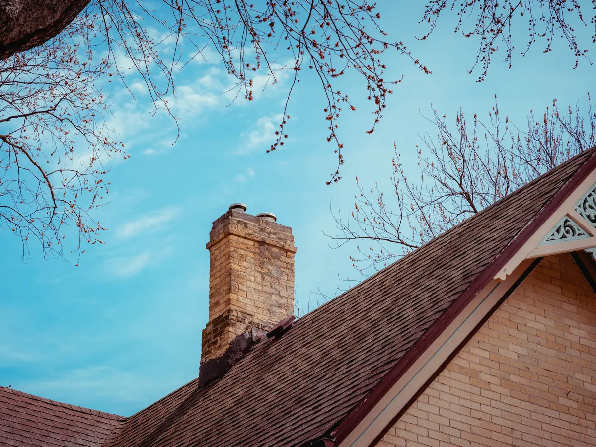 Brick chimney rising above a shingle roof and a decorated gable