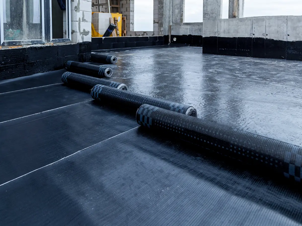 Rolls of new membrane being laid across a flat roof