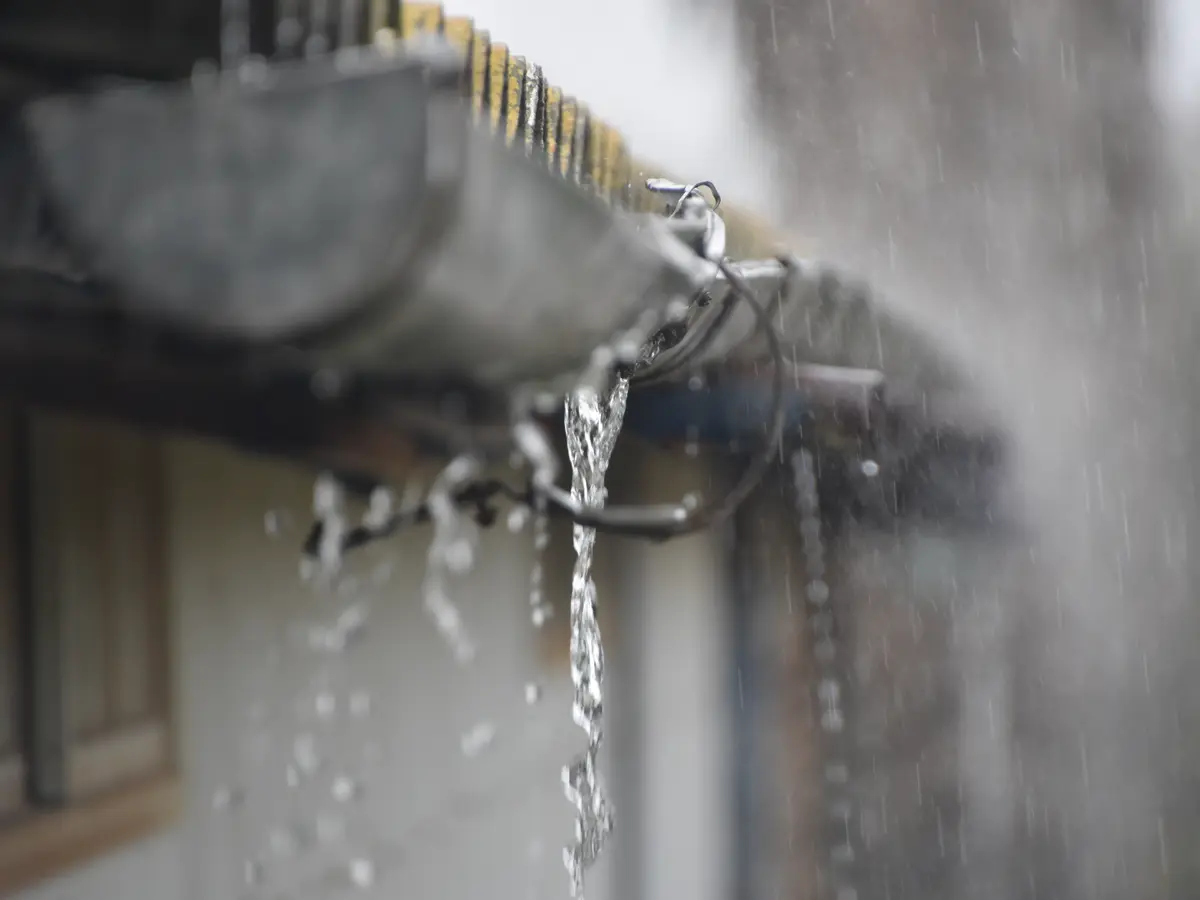 Rain pouring over the edge of an overflowing eavestrough