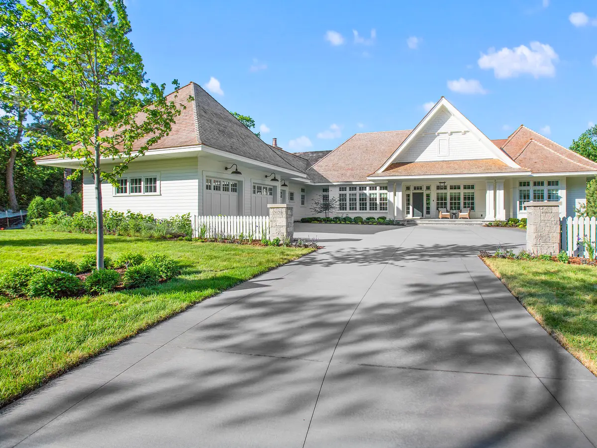 Long concrete driveway leading to a house between lawns
