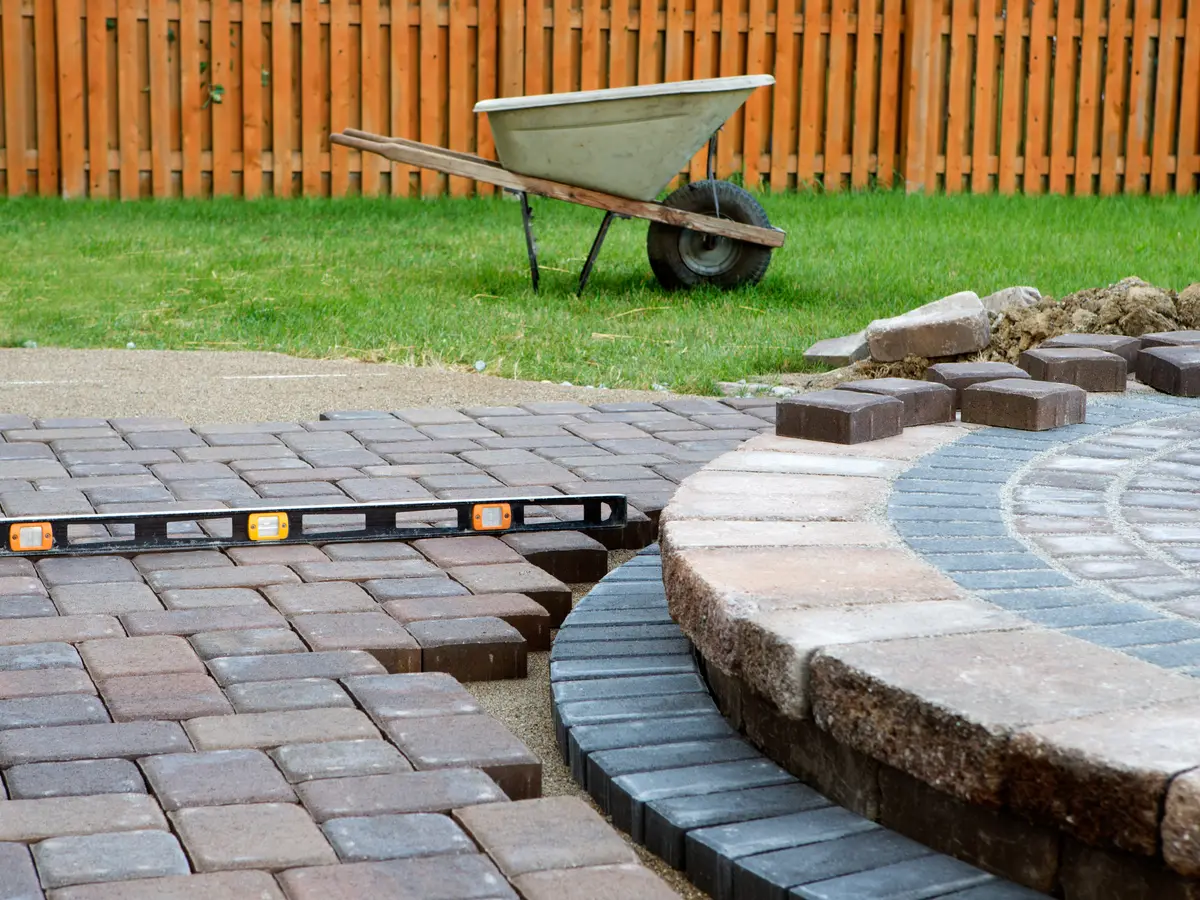 Interlocking pavers being laid with a level beside a circular paver step