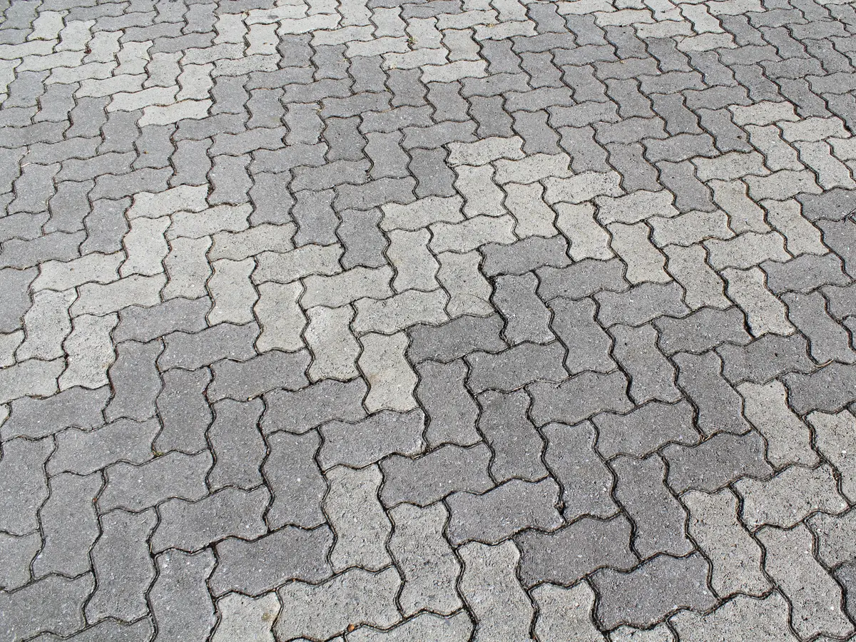 Close view of grey interlocking pavers in a zigzag pattern
