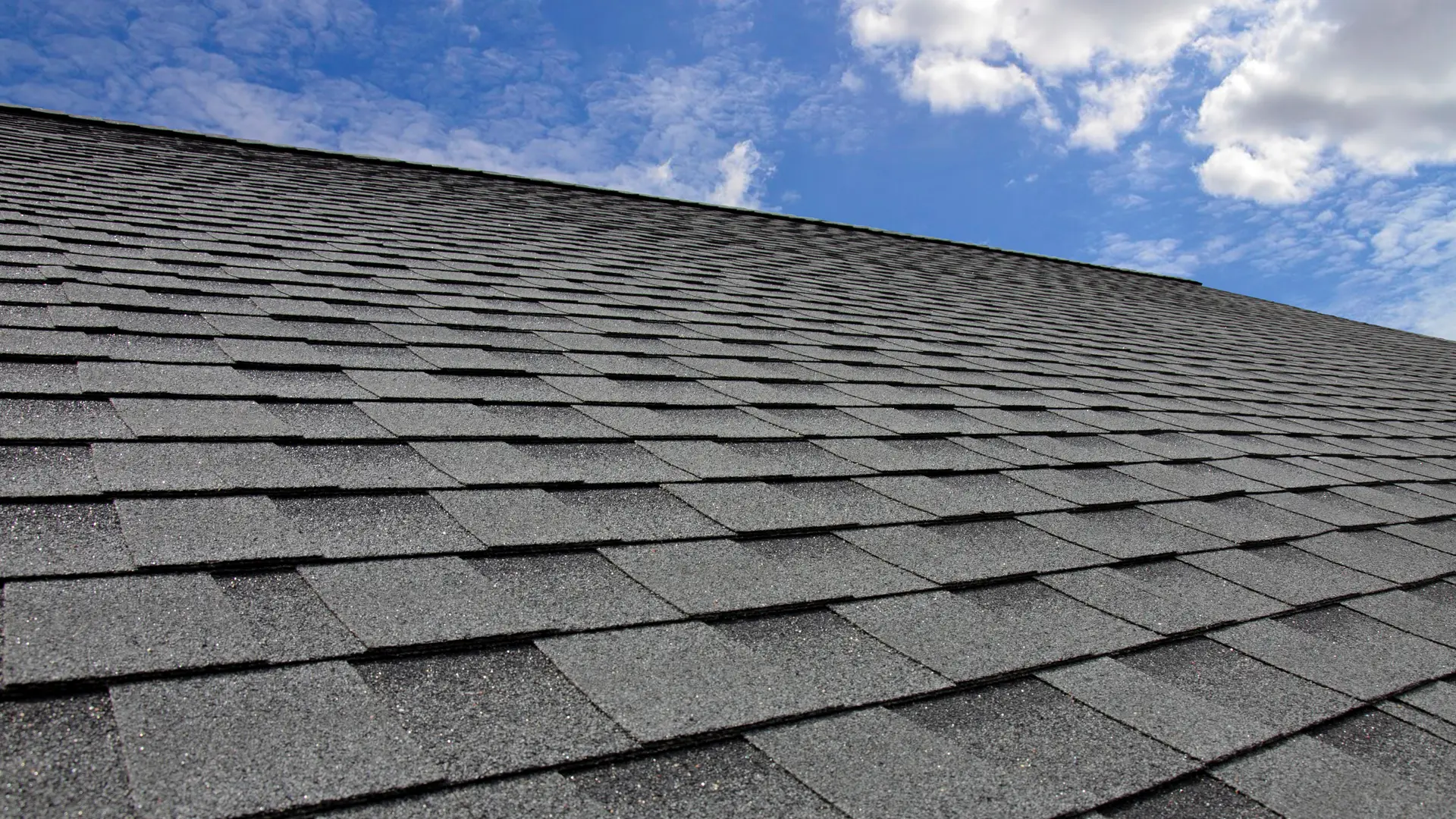 New dark grey asphalt shingle roof against a blue sky